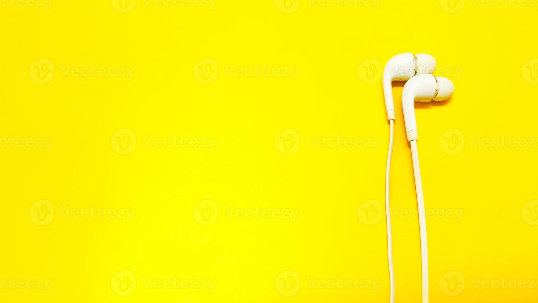 White earphones isolated on yellow background photo