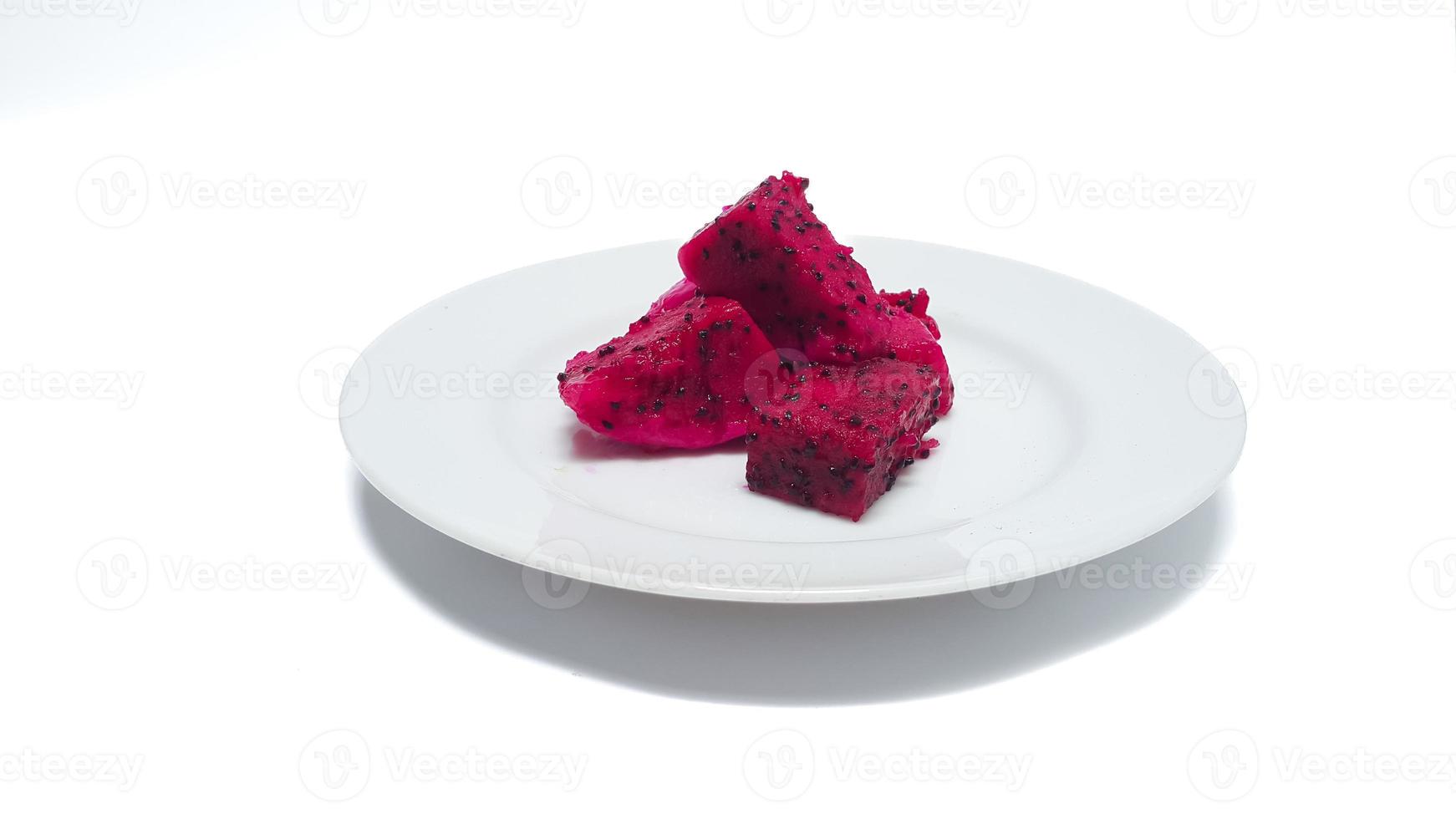 A plate of seductive red dragon fruit. Red dragon fruit, pitaya or pitahaya cut in cubes on white plate. photo
