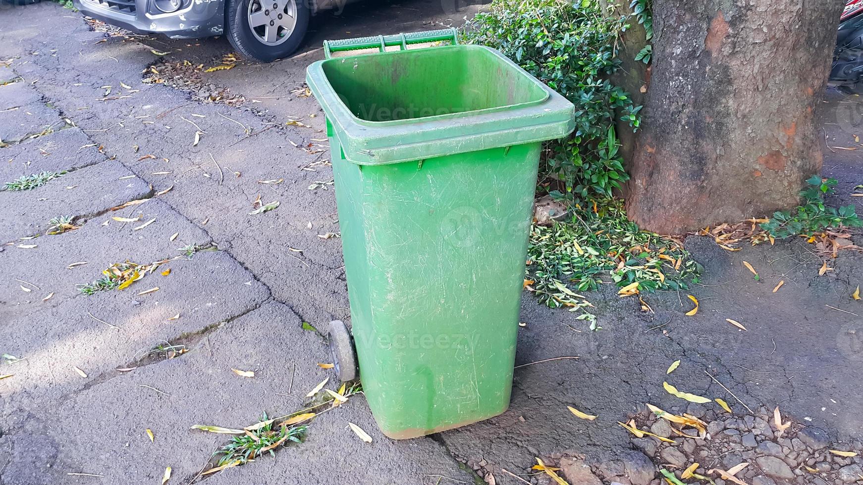 Opened big empty green plastic trash garbage bin. Public trash on the side of the road. photo