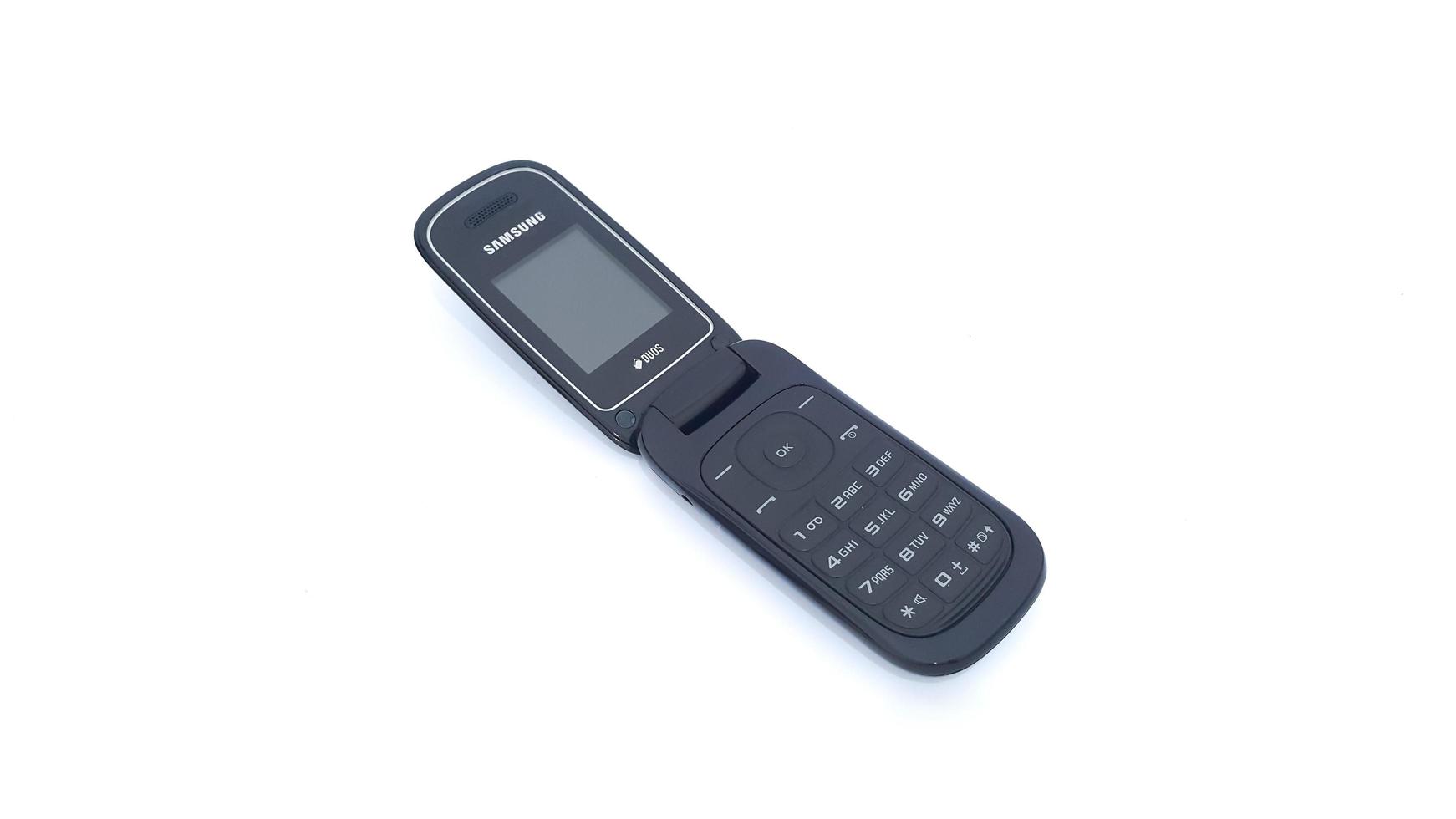 Jakarta, Indonesia, 2023 - Close up of old Samsung flip phone isolated on white background. Obsolete open black Samsung flip cell phone. photo