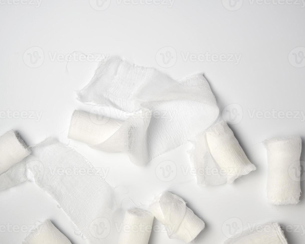 rolled up white sterile medical bandages on a white background photo