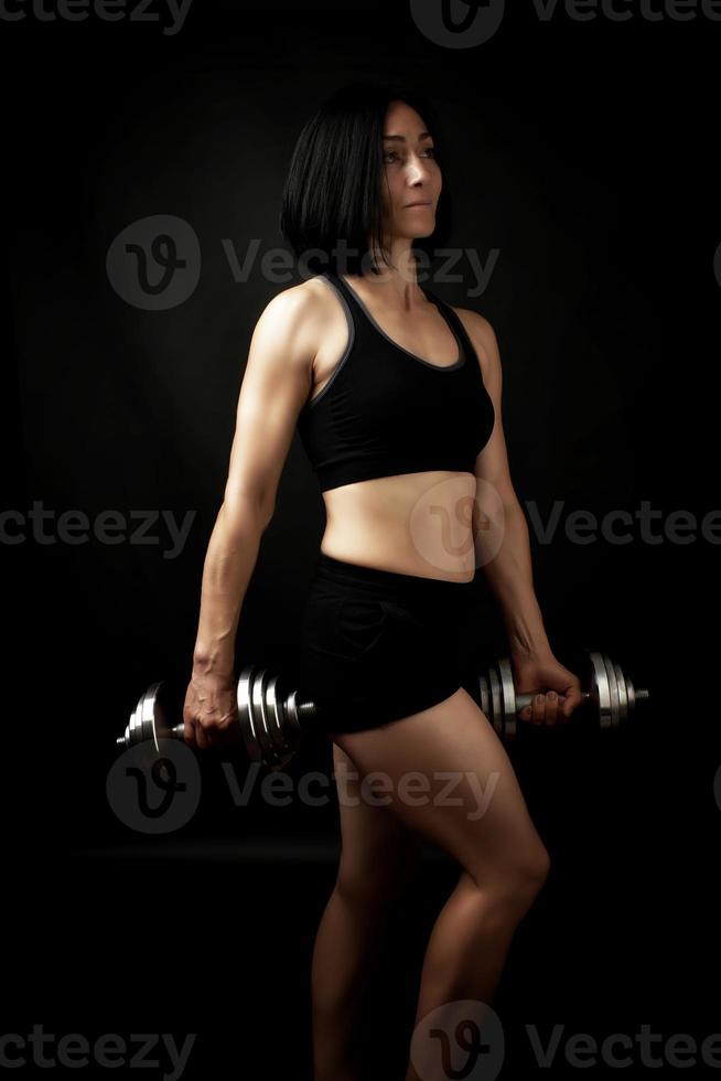 young woman of Caucasian appearance holds steel type-setting dumbbells in her hands photo