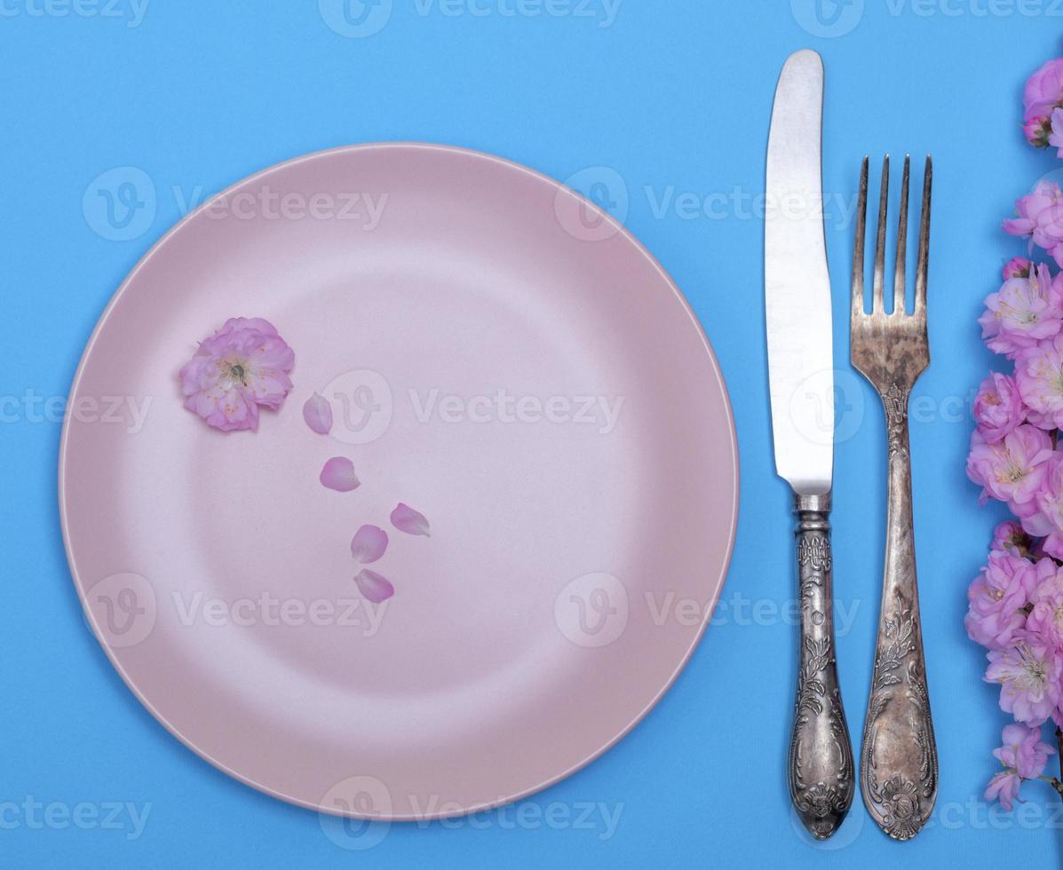 empty round pink ceramic plate and a vintage knife with a fork photo