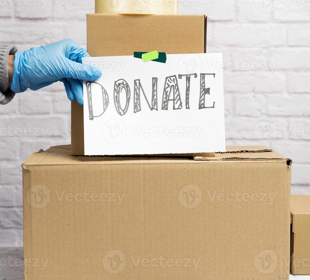 stack of cardboard boxes and white sheet of paper with inscription donate photo