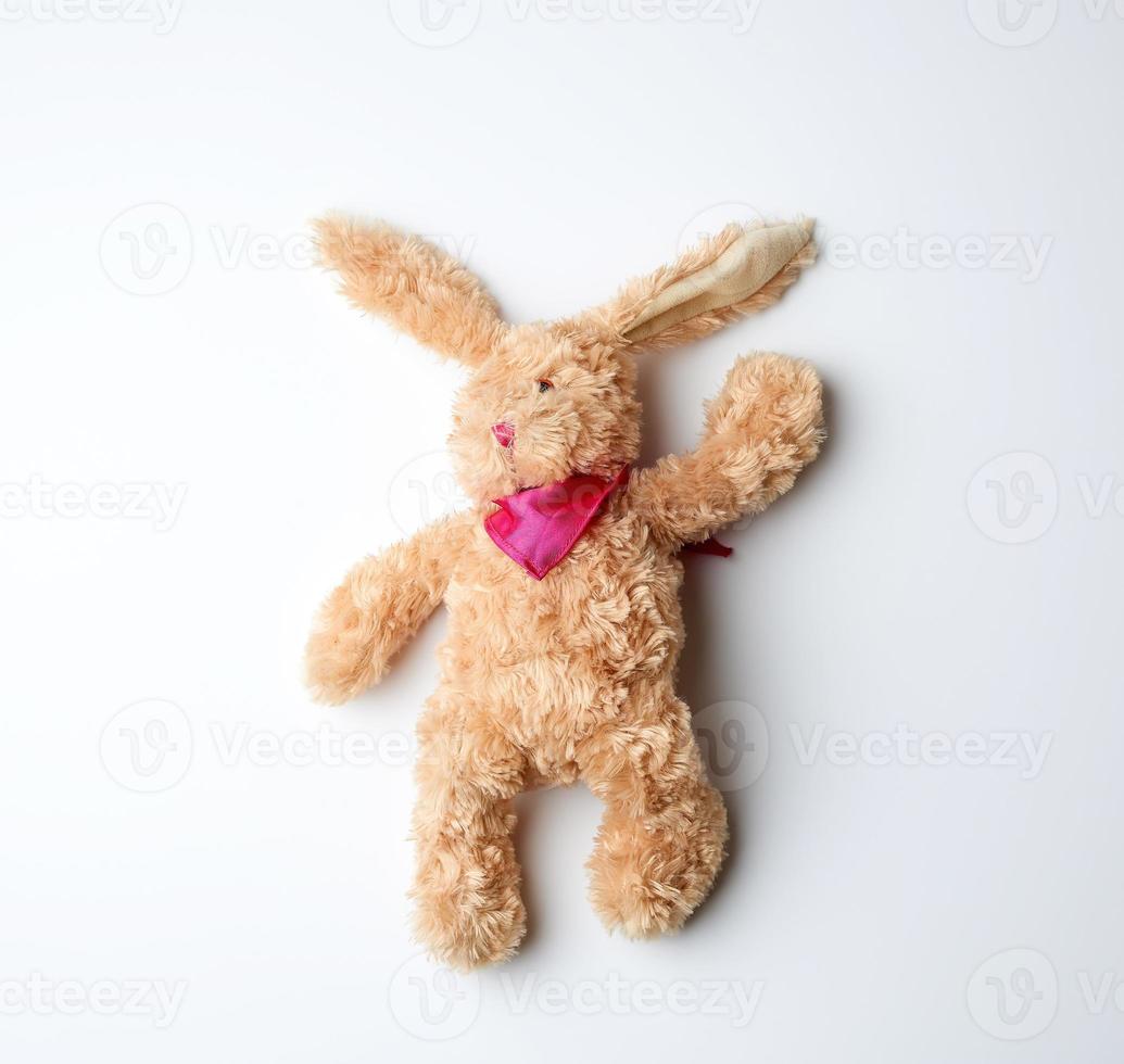 toy brown plush hare lies on a white background photo