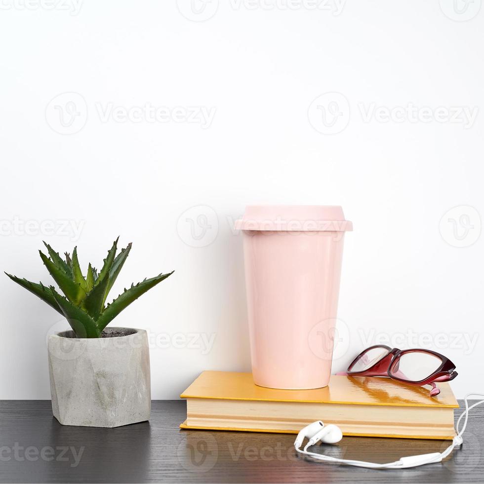 libro cerrado y vaso de cerámica rosa con café sobre una mesa negra foto