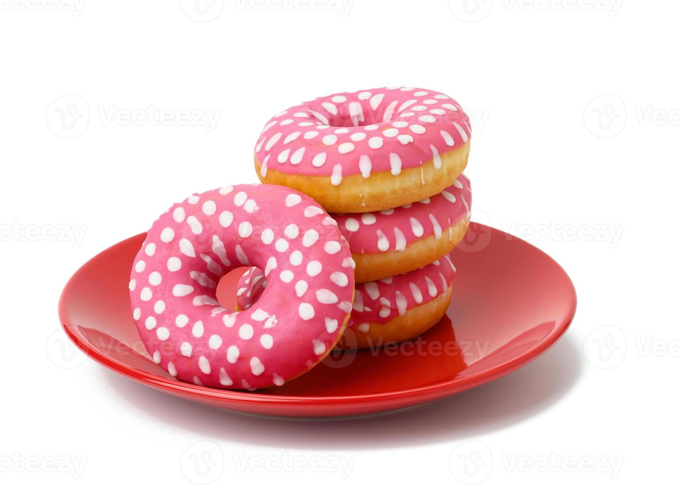 stack of baked donuts with pink frosting on a red round plate, food isolated on blue background photo