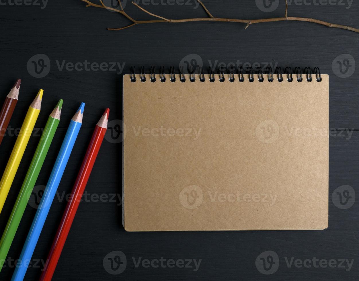 notebook with brown pages and multicolored wooden pencils photo