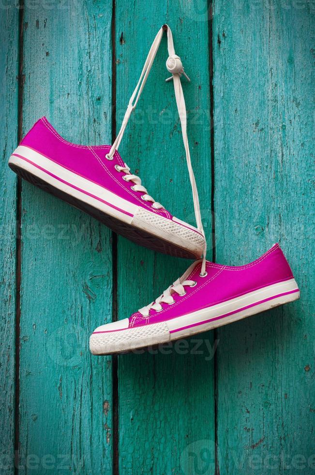 pair of bright pink sneakers hanging on a cord photo