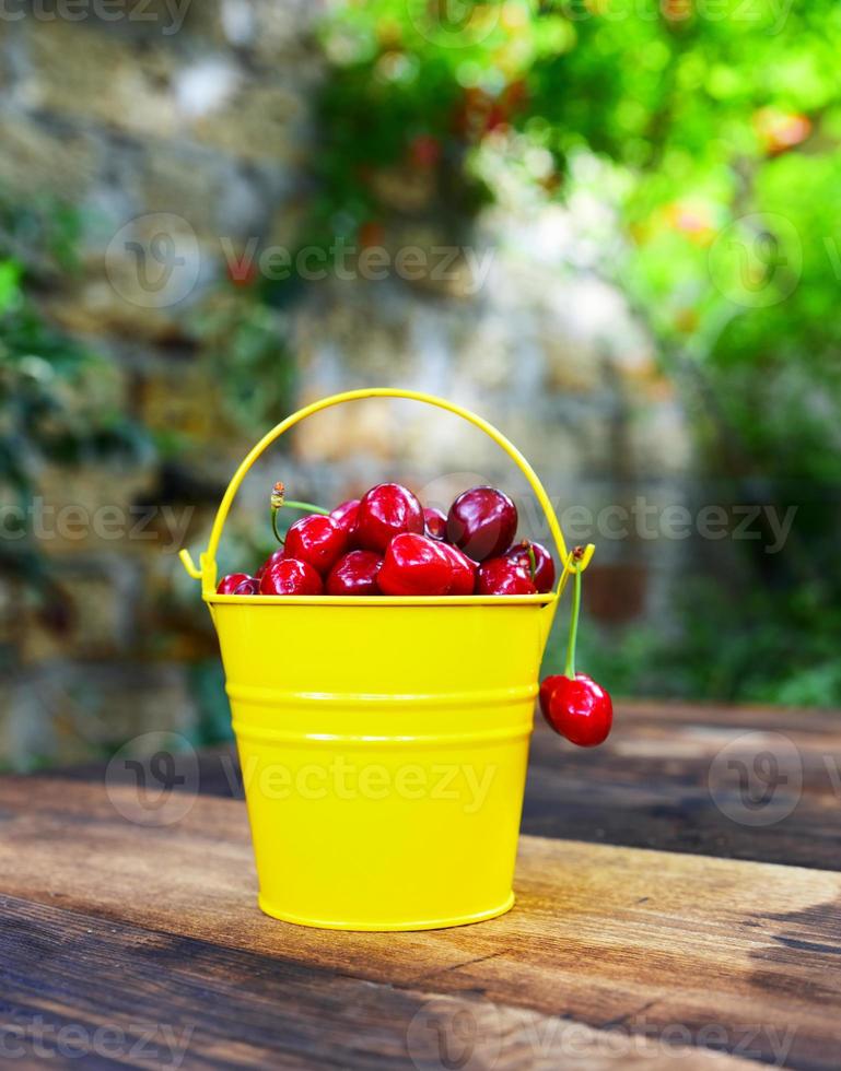 Red ripe cherry in a yellow iron bucket photo