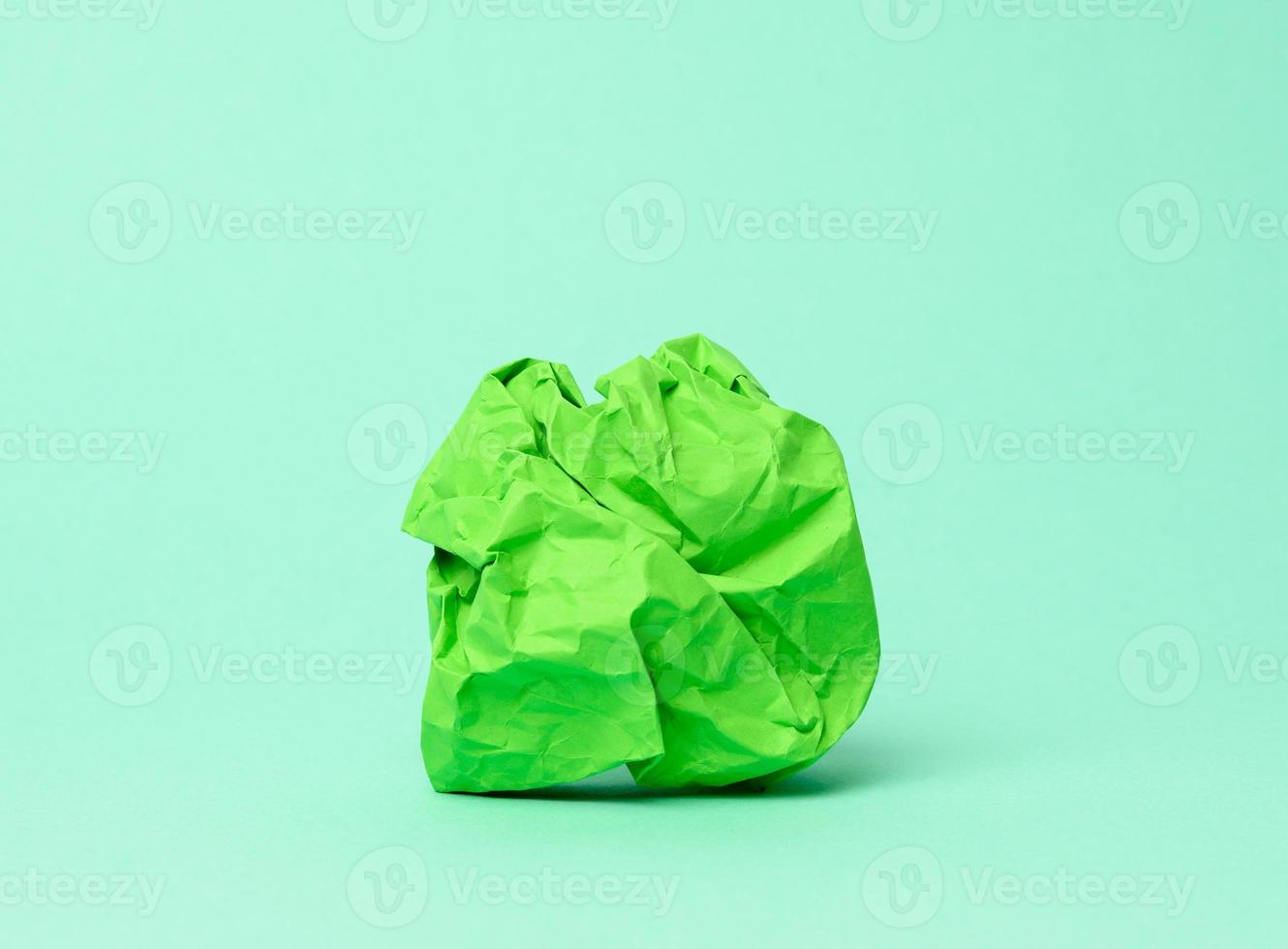crumpled ball of green paper on a green background, photo
