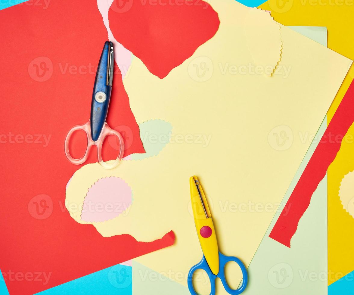 pair of plastic scissors and colored paper for cutting figures photo