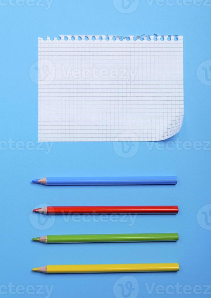 white blank sheet in a box from a notebook with holes and multi-colored wooden pencils photo