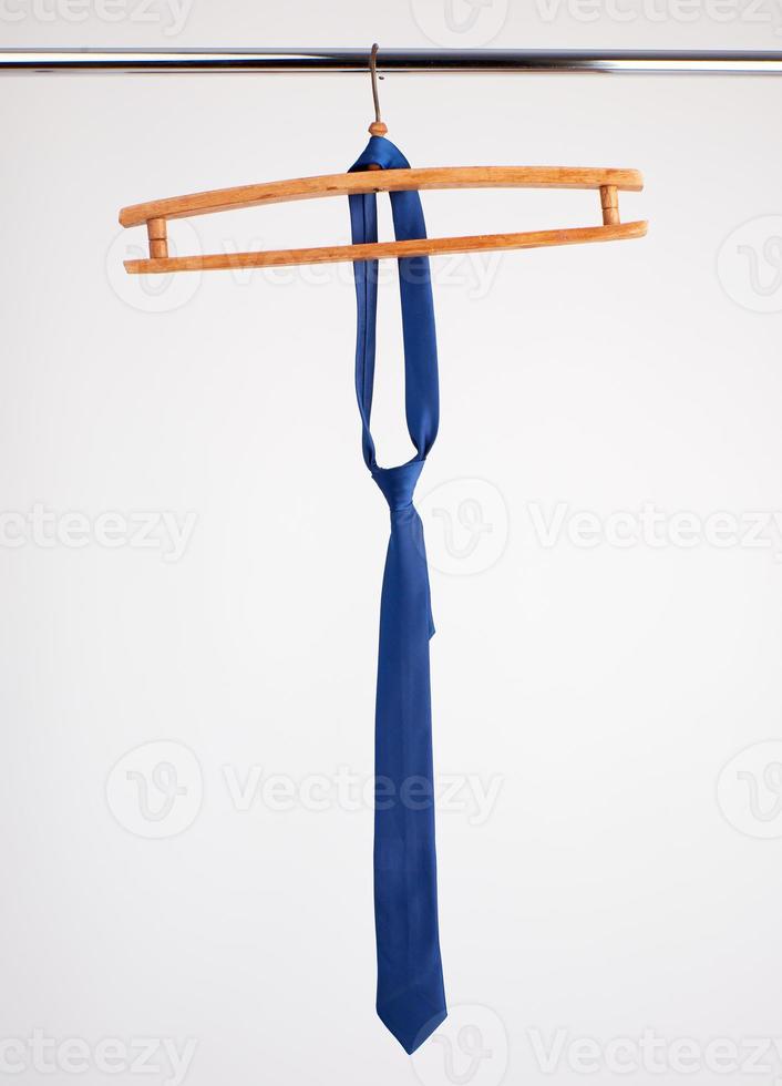 blue tie hanging on a wooden hanger photo