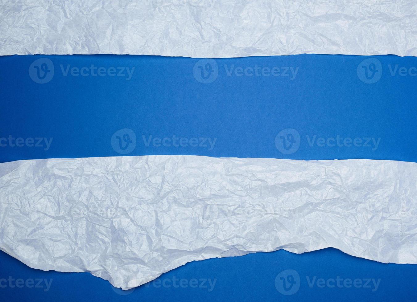 blue background with white crumpled torn paper elements photo