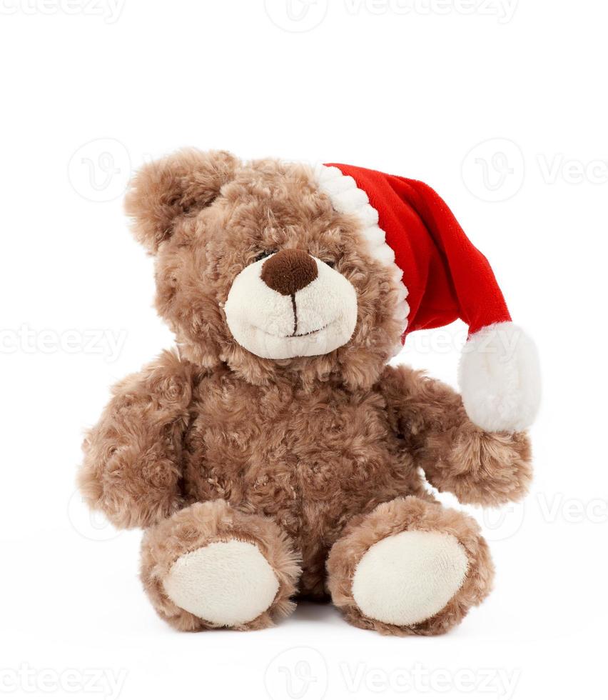 little cute brown teddy bear with in a red Christmas hat sits photo