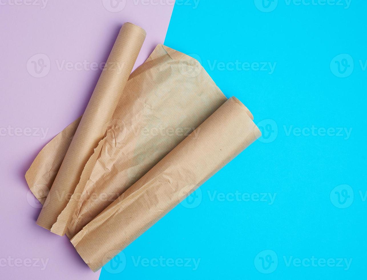 two rolled rolls of brown parchment baking paper on a colored background photo