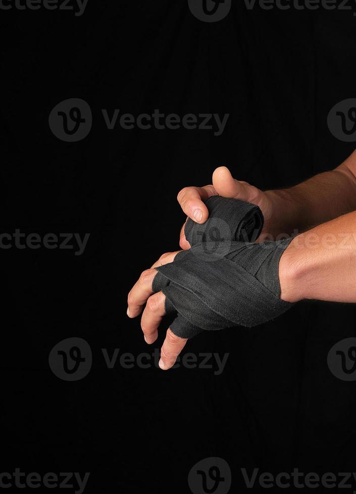 man wraps his hands in black textile bandage for sports photo