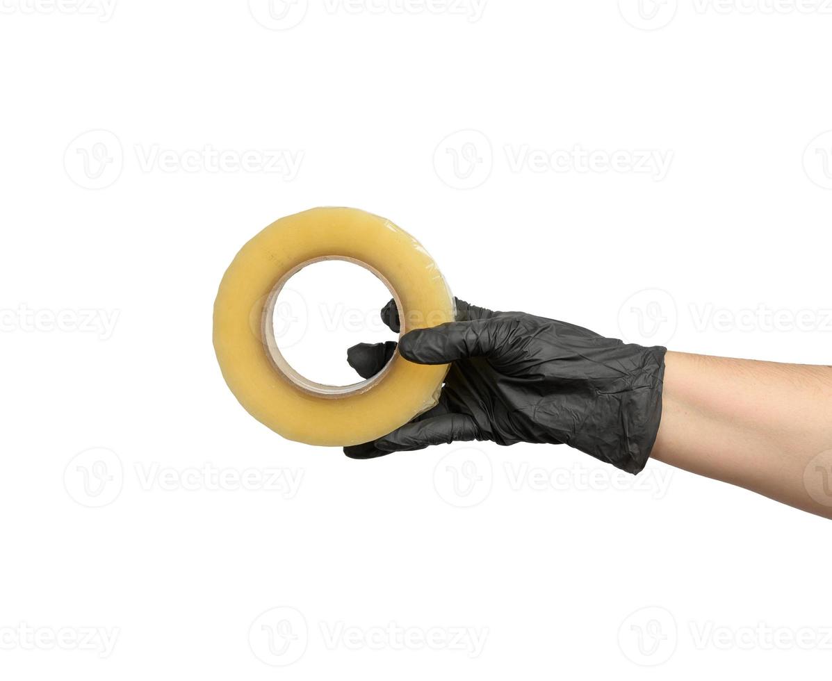 female hand in black latex glove holds roll of transparent  tape photo