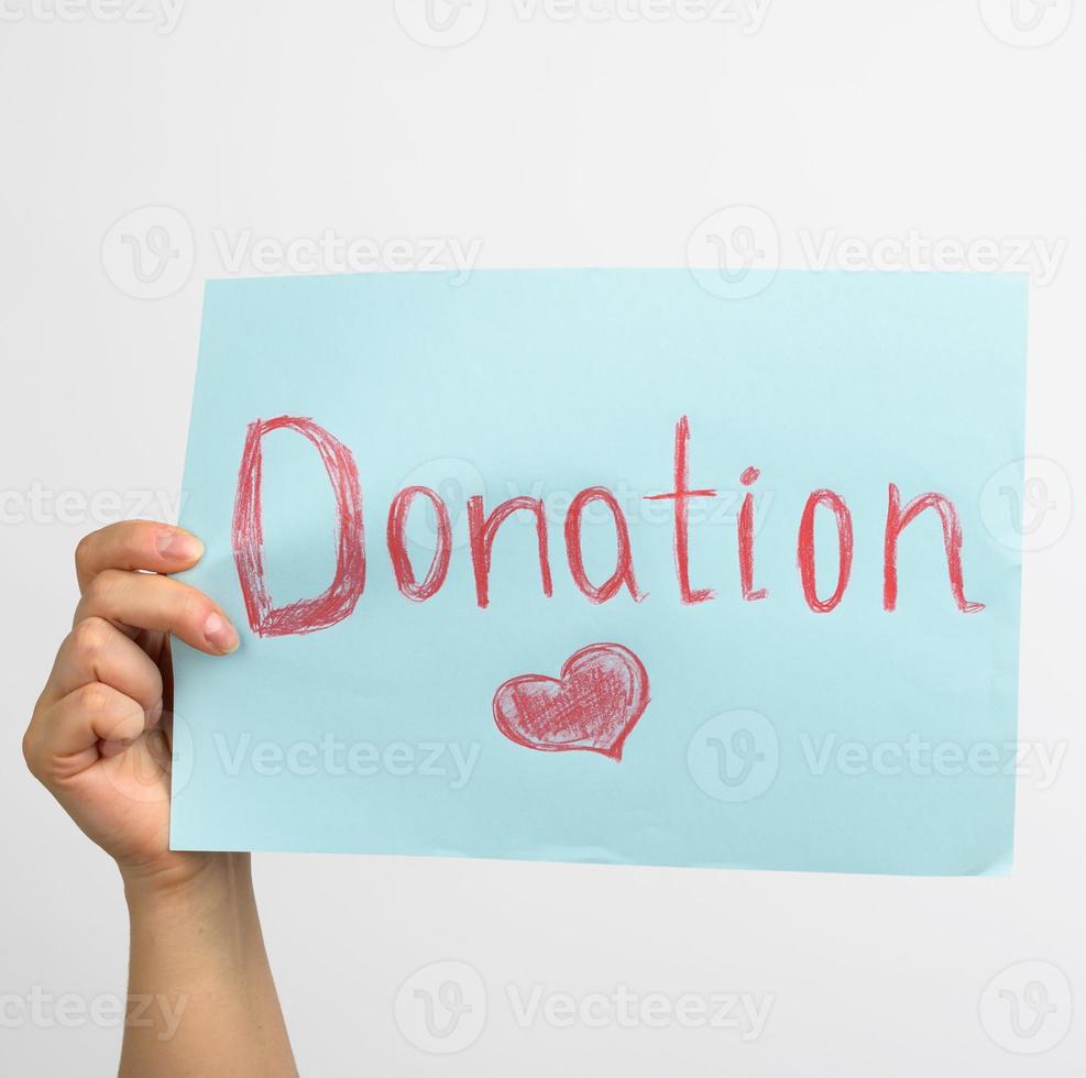 female hand holding a blue piece of paper with the inscription donation on a white background photo