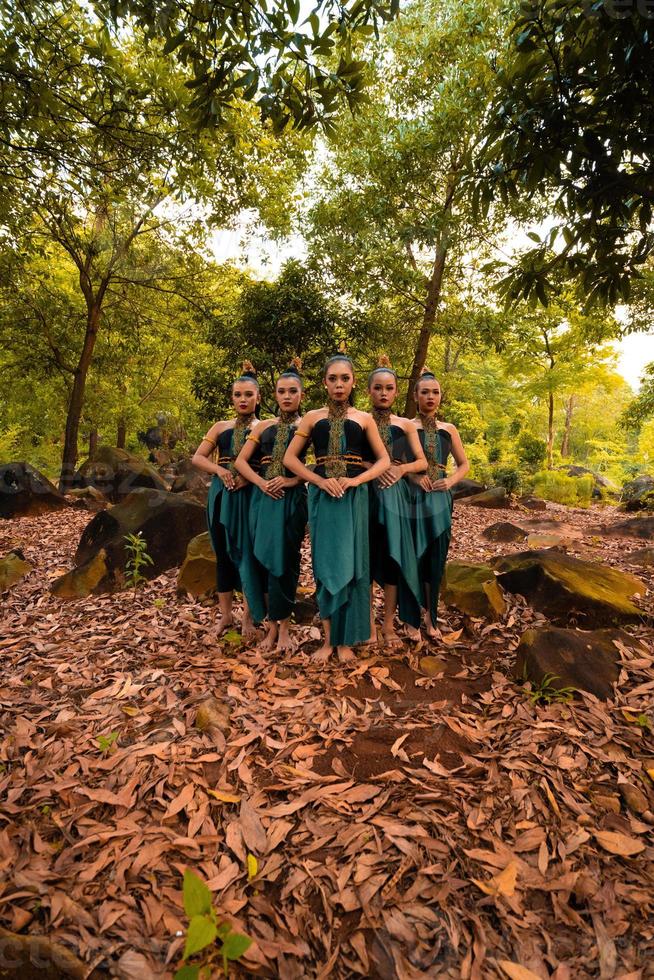 A Beautiful Asian woman in a green costume standing together in front of the forest with brown leaves photo