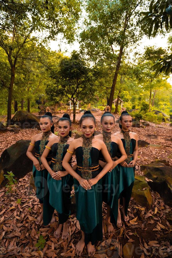 Glamor Asian women with green costumes and makeup line up together in the jungle with brown leaves on the ground photo
