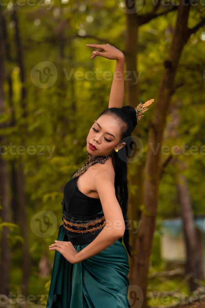 A brave Asian woman in makeup wearing a green costume and gold jewelry with the woods in the background photo