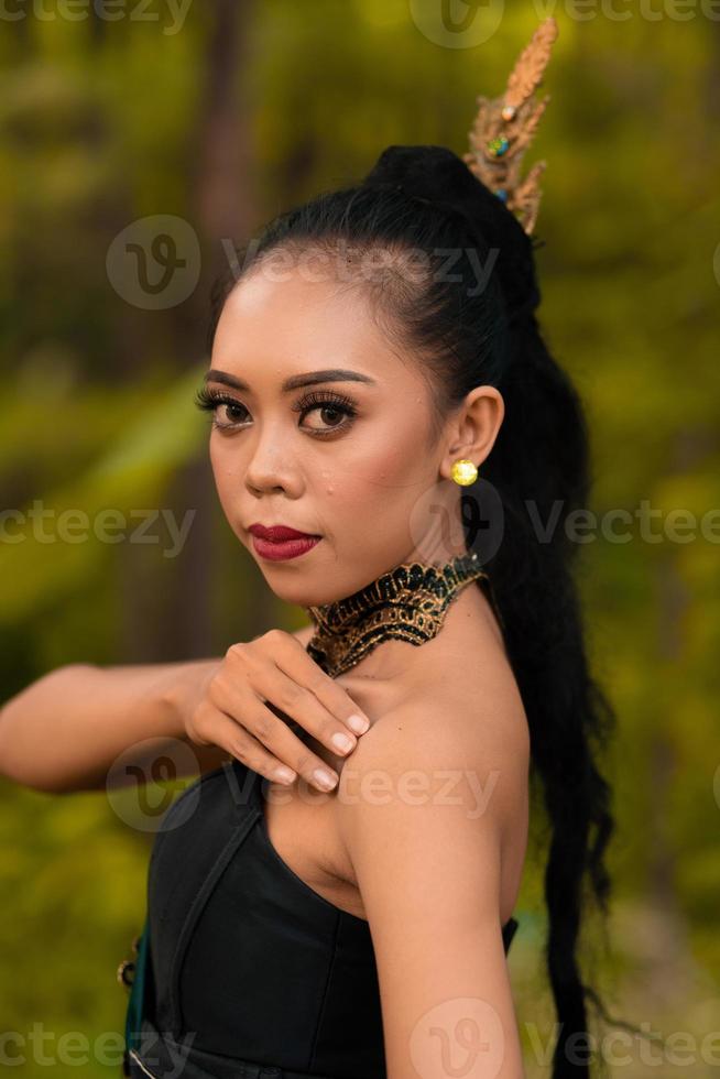 Portrait of a mystical woman in makeup with black hair and wearing a gold jewelry photo