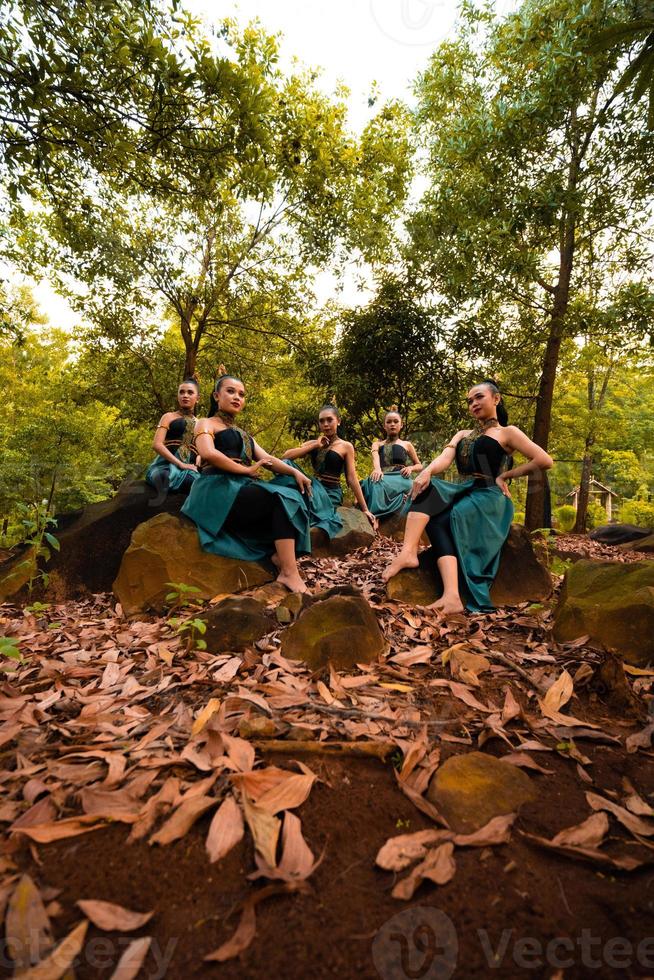 un grupo de mujeres asiáticas se va de vacaciones al bosque mientras usa una falda verde y se sienta en una roca foto