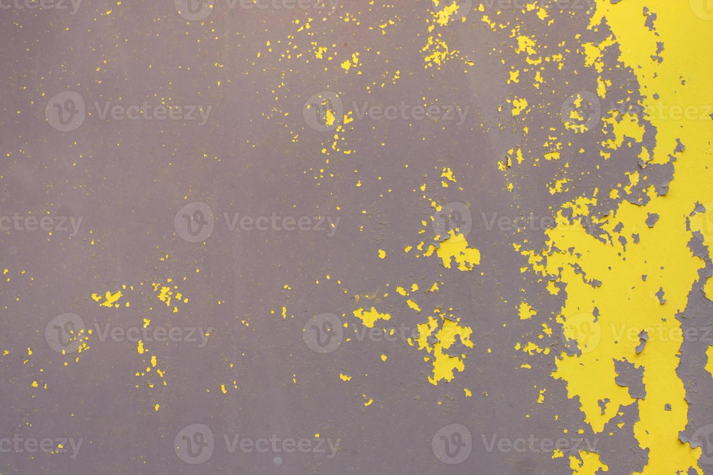 Old yellow grungy metal wall with peeling paint and rusty spots, industrial background photo texture
