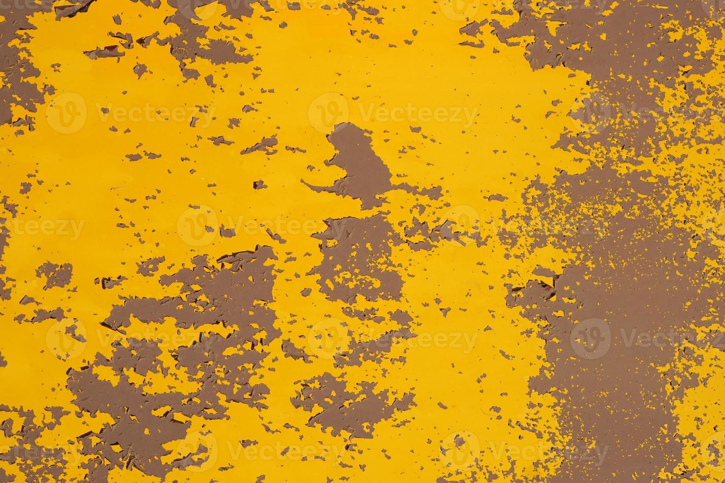Old yellow grungy metal wall with peeling paint and rusty spots, industrial background photo texture