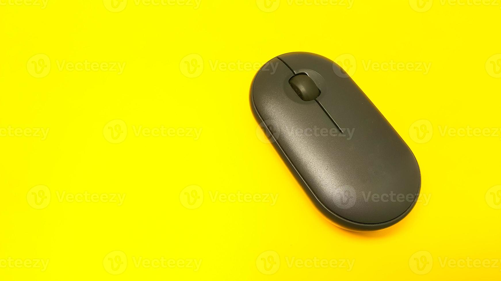 Black wireless mouse on yellow background photo