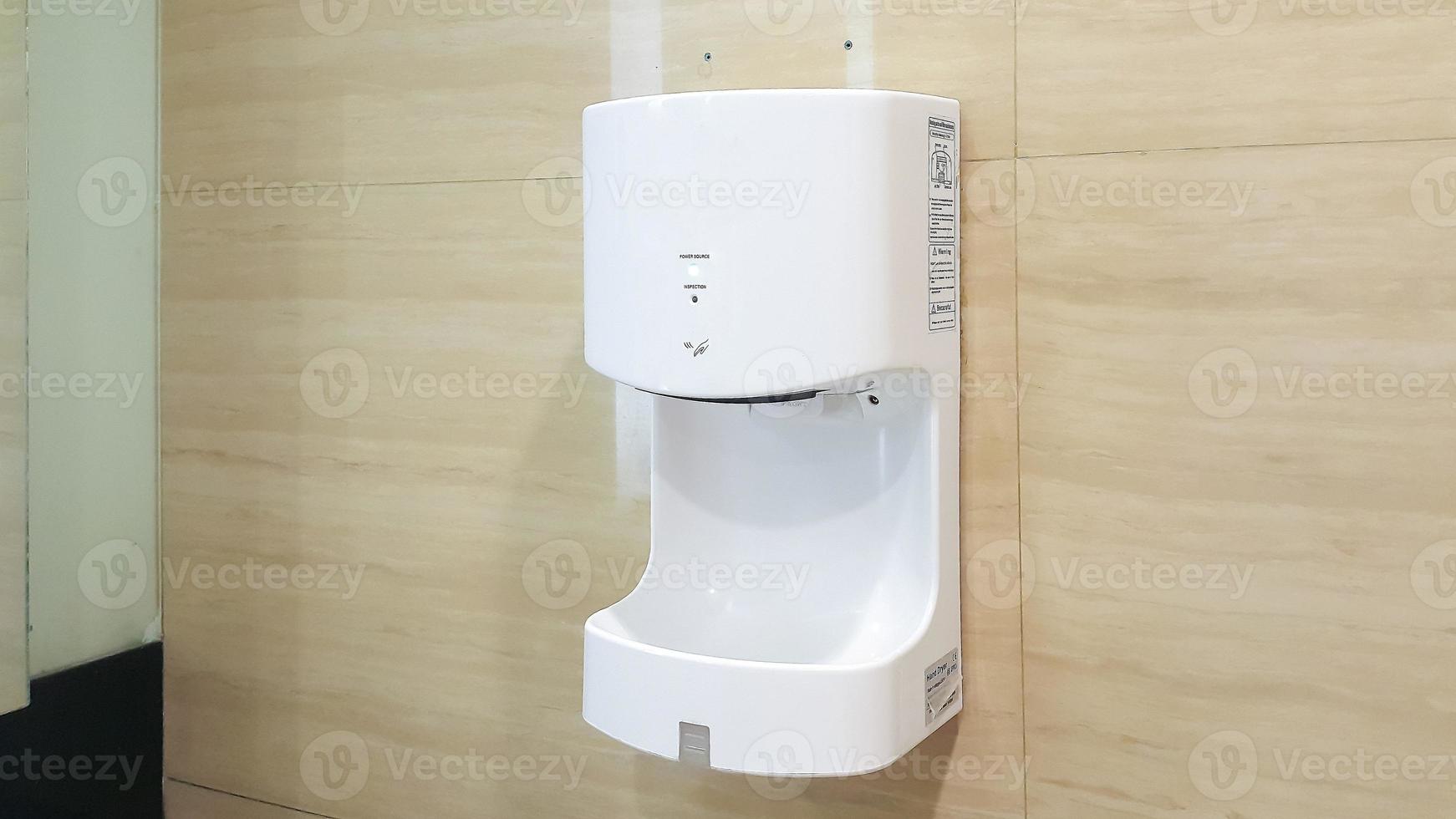Close up of automatic hand dryer in public toilet or restroom photo
