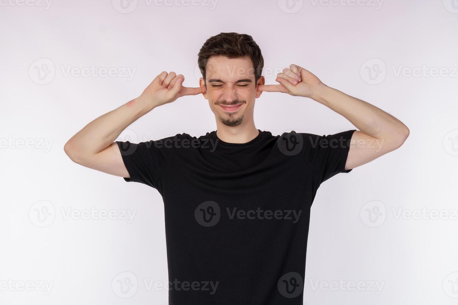 Portrait of attractive man close ears from noisy neighbours, looking up and shouting annoyed, hearing loud music on isolated background. photo