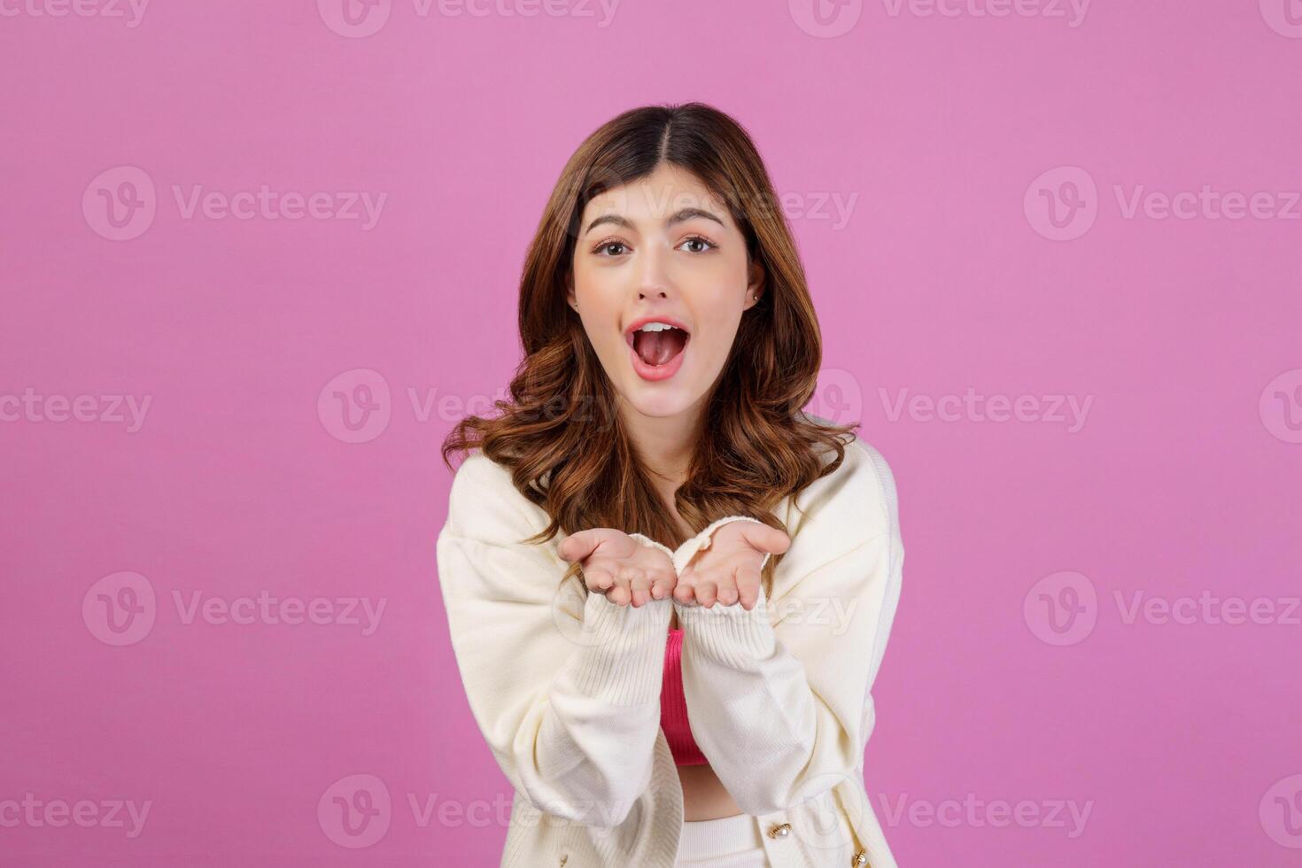 Portrait of Surprised young woman presenting or showing open hand palm with copy space for product over isolated pink background photo