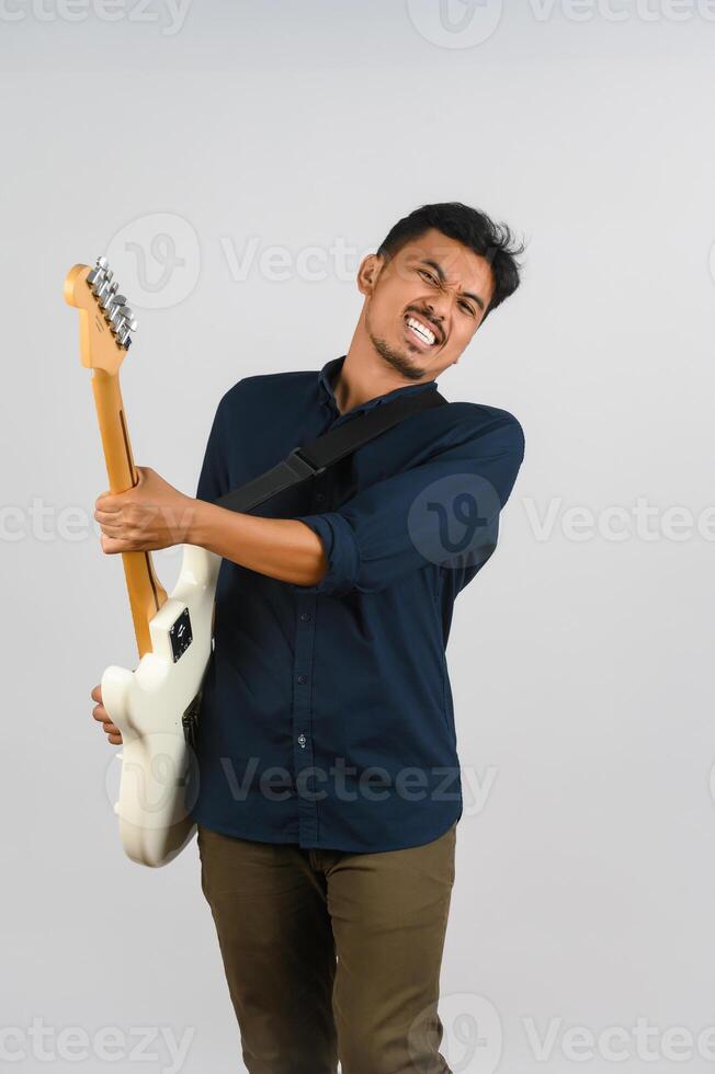 Portrait of Young Asian man in blue shirt with electronic guitar isolated on white background photo