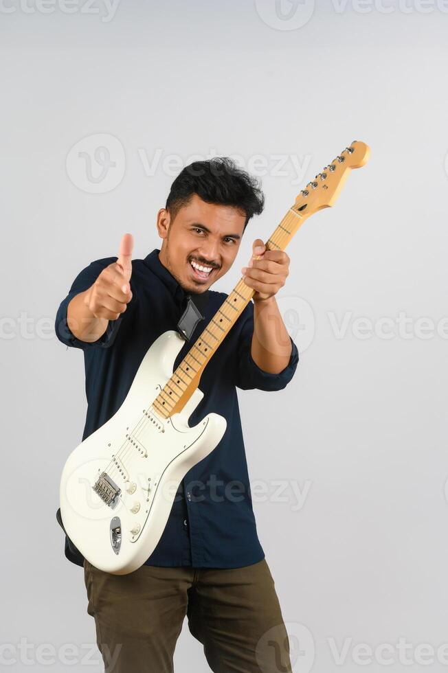 Portrait of Young Asian man in blue shirt with electronic guitar isolated on white background photo