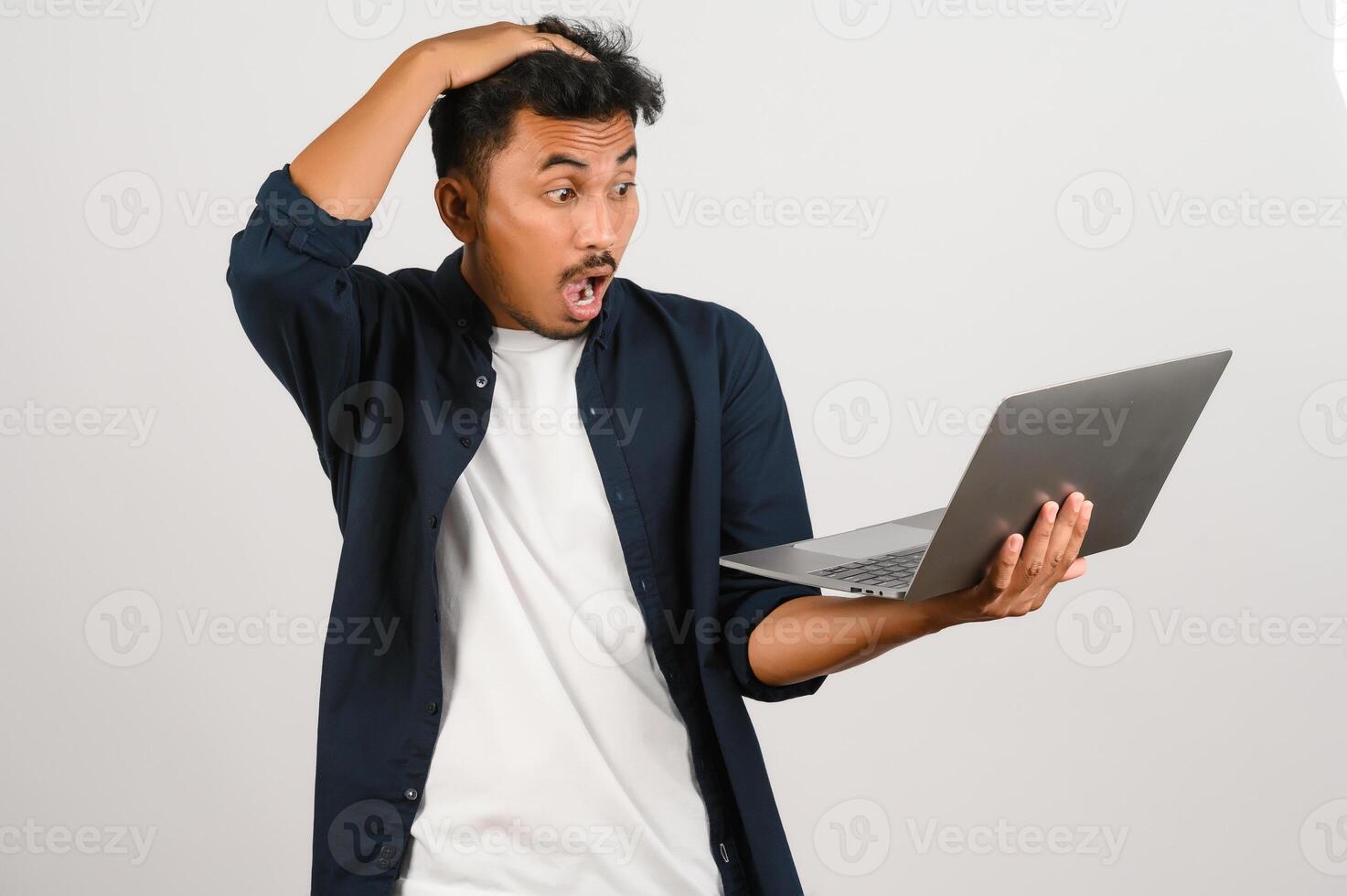 Portrait of shocked asian businessman working on laptop computer isolated over white background photo