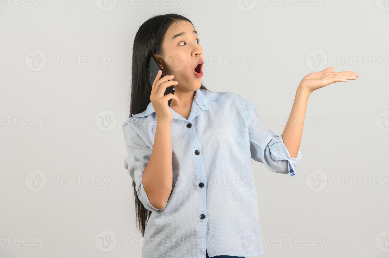 Portrait of Young asian woman talking on mobile phone while standing isolated over white background photo