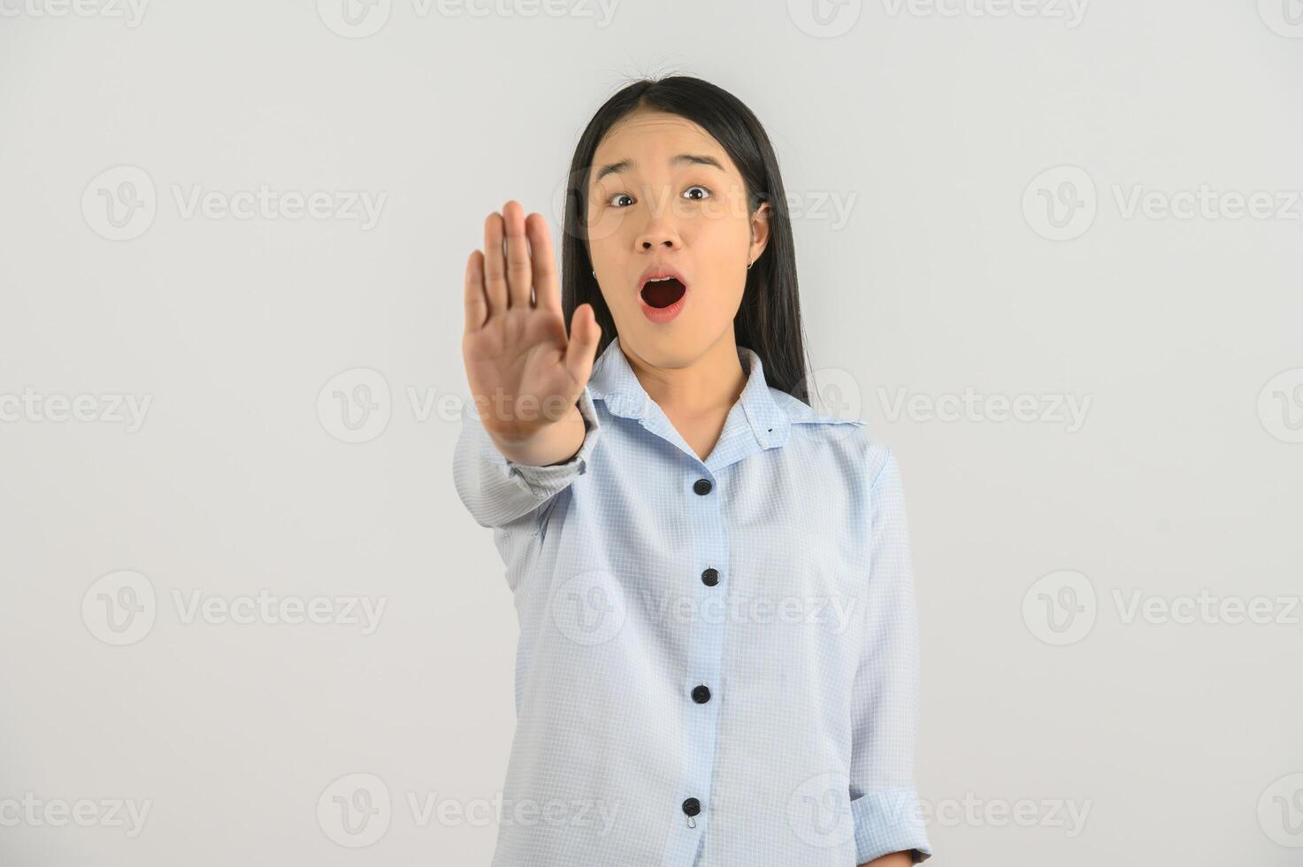 Portrait of Excited young asian woman in blue shirt showing hand foreground and looking at camera isolated on white background photo