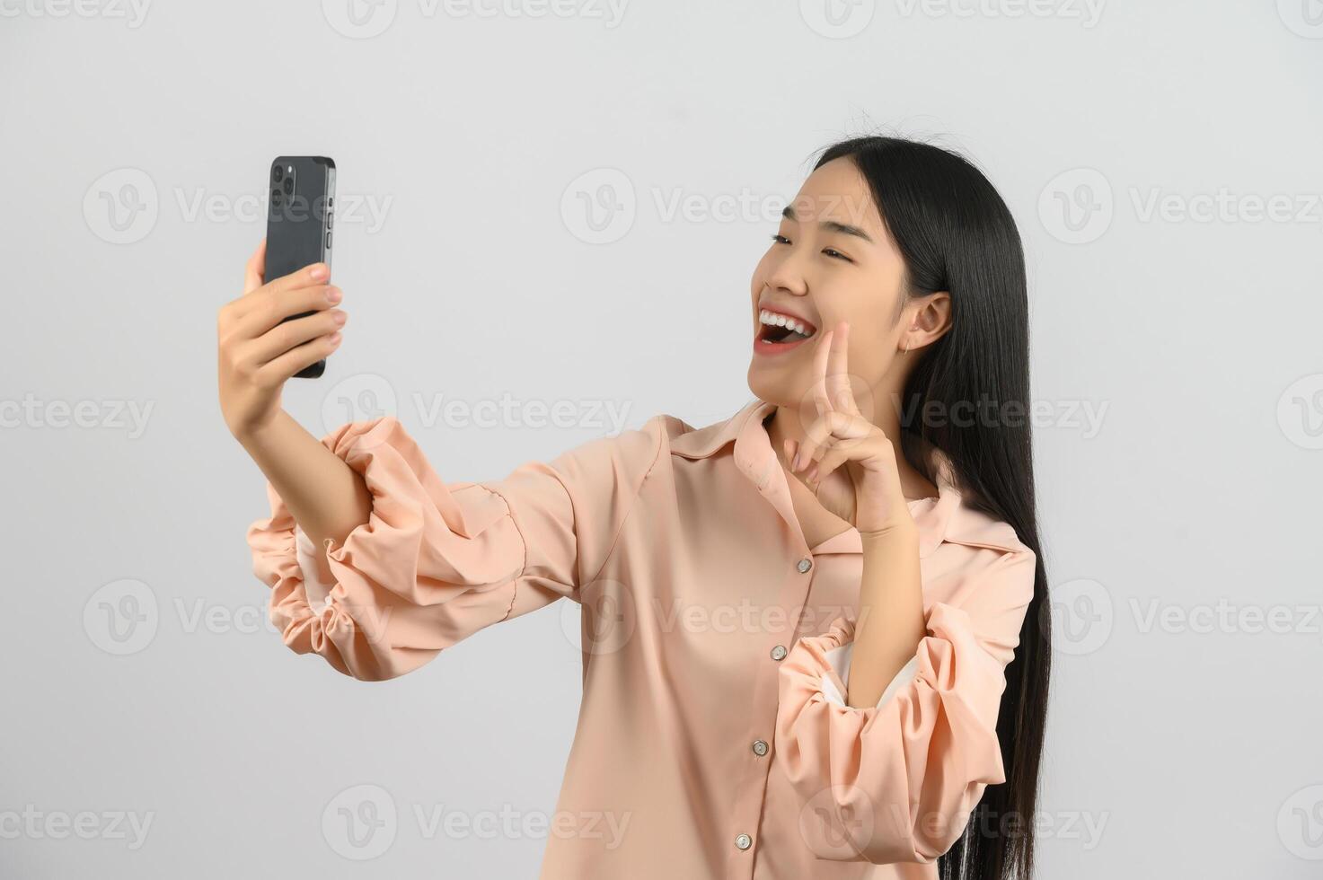 Protrait of Young asian woman expressing surprise while using mobile phone isolated over white background photo