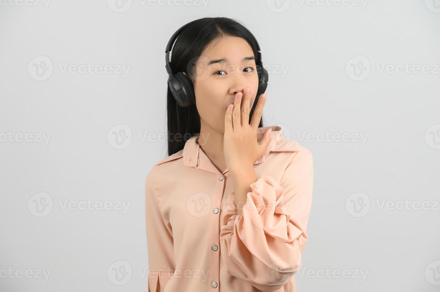 Portrait of young asian woman enjoying listening to music with large headphones in studio isolated on white background photo