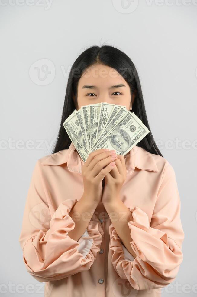 Portrait of a cheerful young woman holding money banknotes and celebrating isolated over white background photo