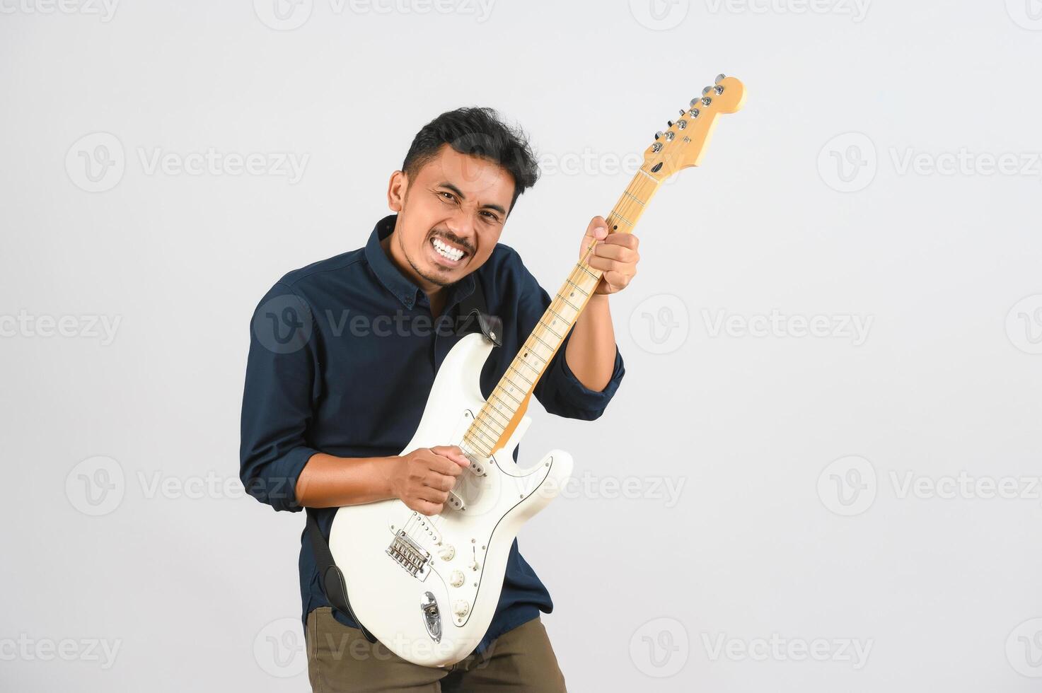 Portrait of Young Asian man in blue shirt with electronic guitar isolated on white background photo