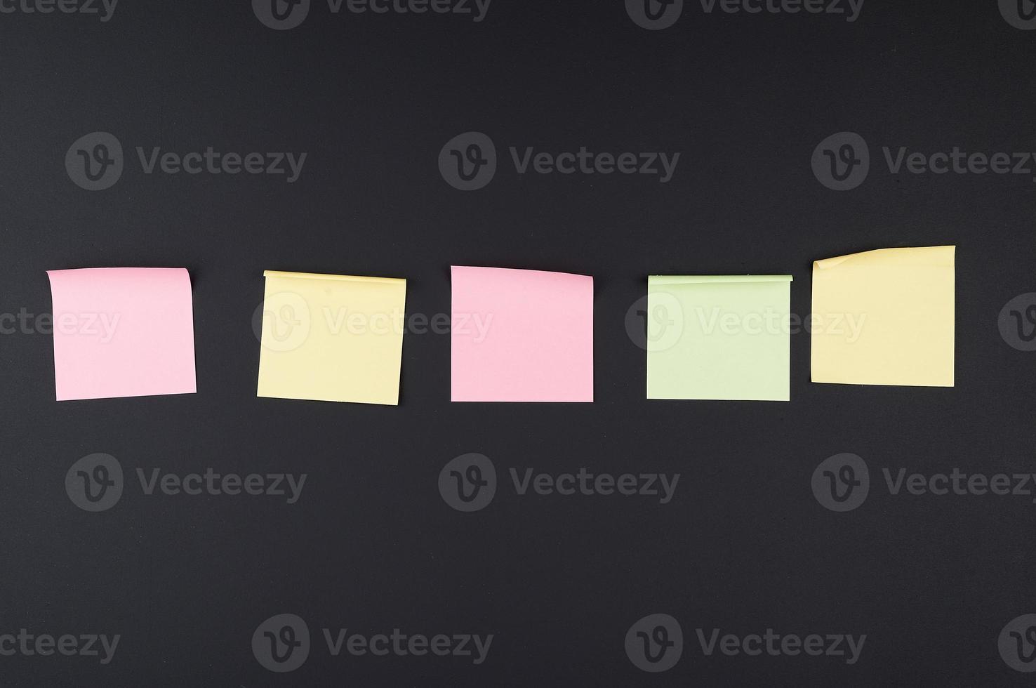 empty square multi-colored stickers hang on a black board photo