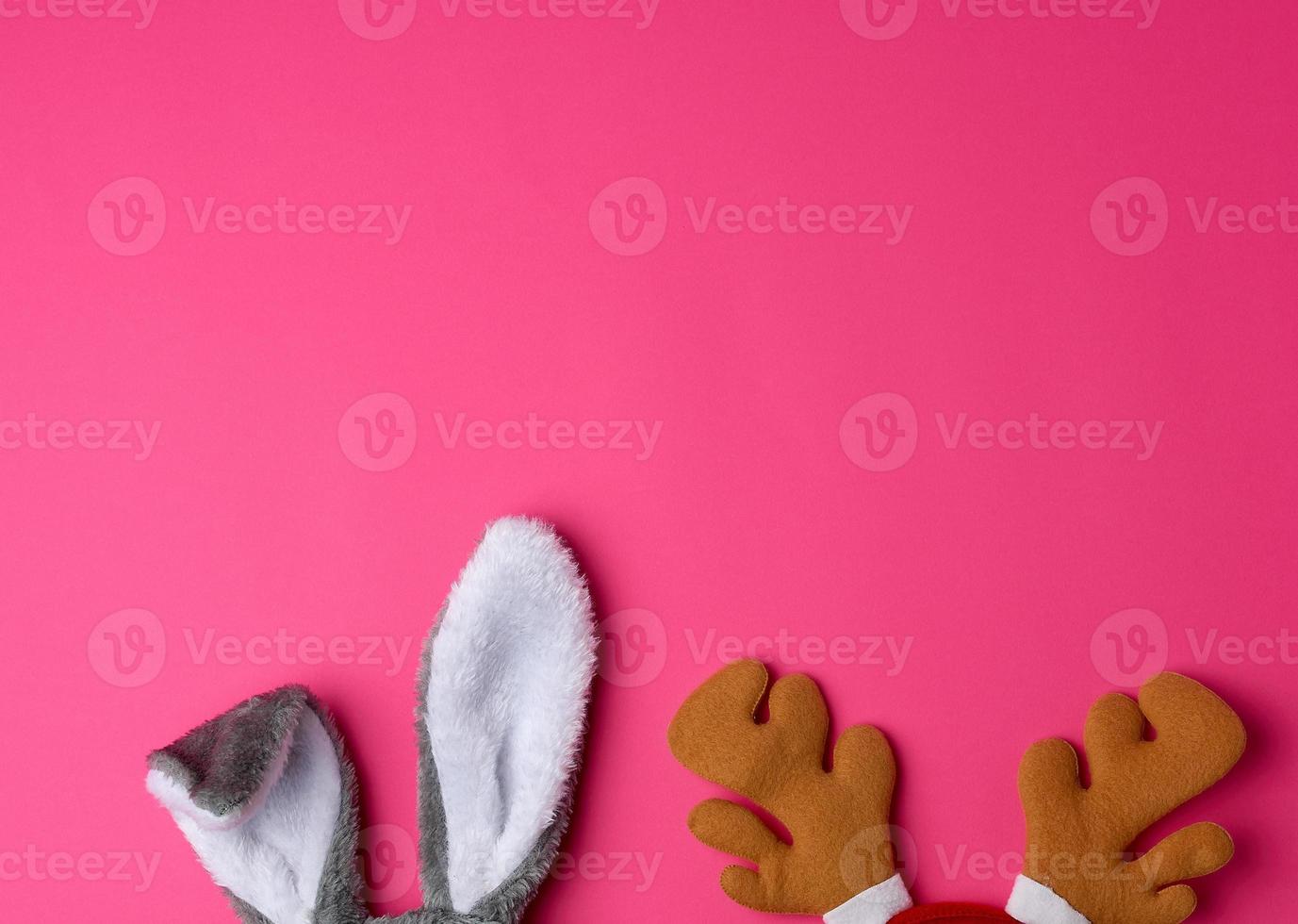 protruding ears of a rabbit mask and brown deer horns on a pink background photo