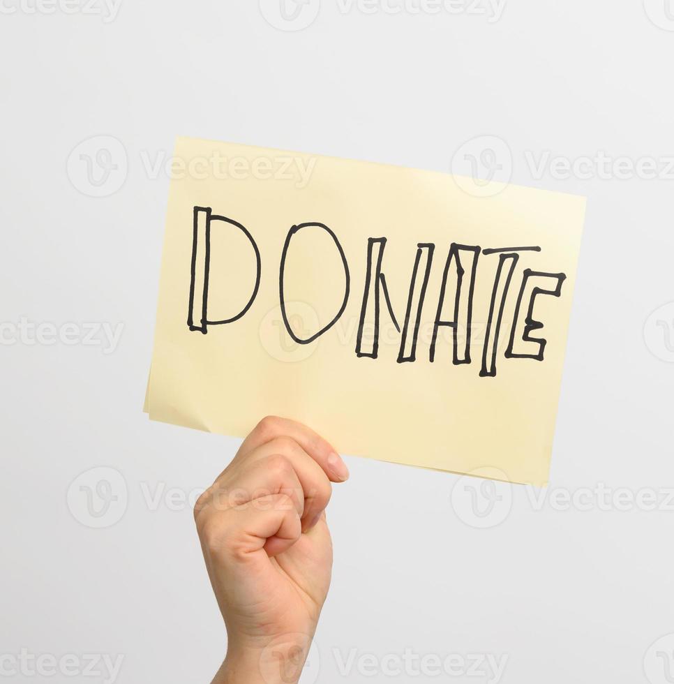 female hand holding a piece of paper with the inscription donate photo