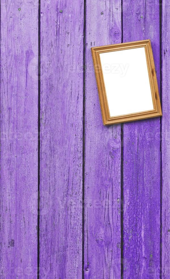 Lilac wooden wall on which hangs an empty wooden photo frame