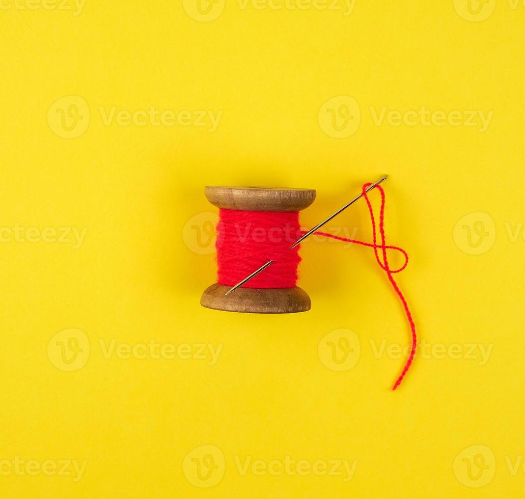 wooden reel with red wool thread and a large needle photo