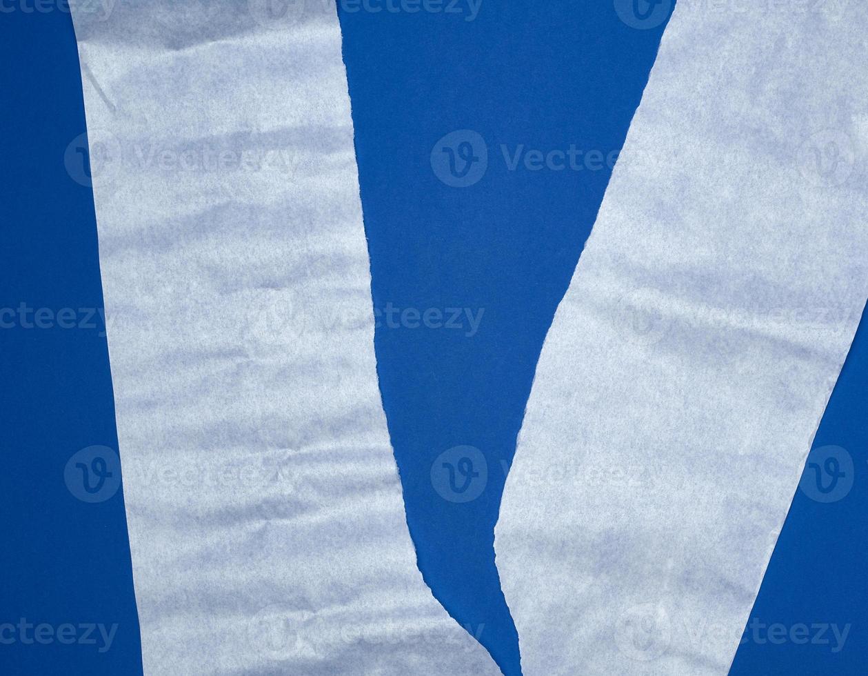 torn piece of white parchment paper on a blue background photo